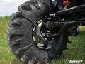 Close-up of a rugged off-road tire with deep treads on grass, revealing the suspension, axle, and brake components installed with the Polaris RZR 800 4 Portal Gear Lift. The SuperATV logo is visible in the bottom right corner.