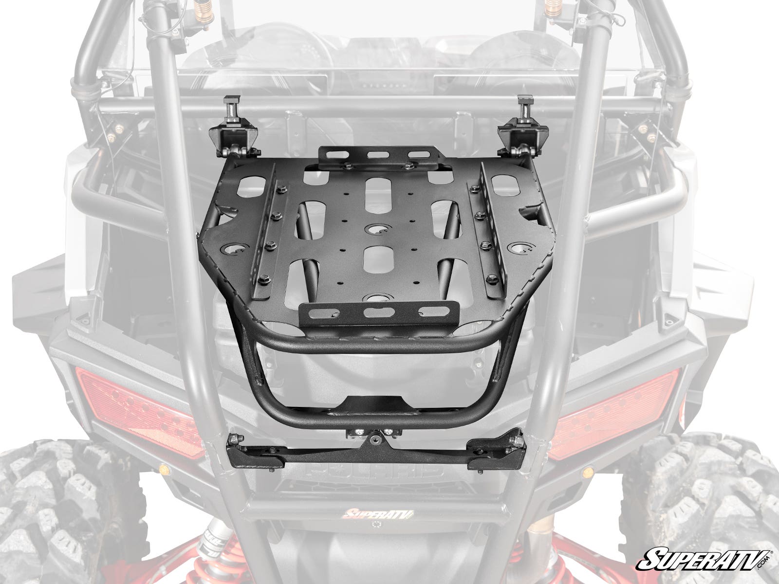 The Polaris RZR Trail S 900 Cargo Rack Alpha, a black metal rack with multiple slots and holes for gear, is mounted to the rear roll cage of an off-road vehicle. Two top clamps secure attachment. The “SuperATV” logo appears in the bottom right corner.