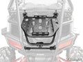 A black Polaris RZR Trail S 1000 Cargo Rack Alpha is mounted on the rear frame of a gray off-road ATV. The rack features multiple slots, bolt holes, and two top clamps for securing items. The SuperATV logo is in the bottom right corner.