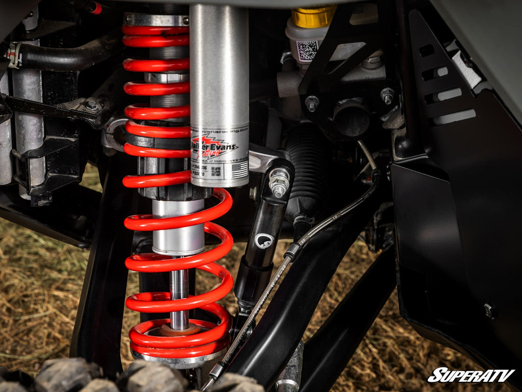 Close-up of a Polaris RZR Turbo R Sway Bar Shock, showing a large red coil spring, silver shock absorber marked ZBROZ RACING, black metal parts, and the SuperATV logo in the bottom right.