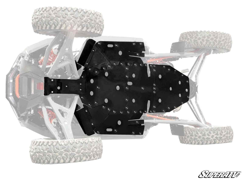 View of a Polaris RZR Turbo R Full Skid Plate in solid black installed beneath the vehicle, with large rugged tires and suspension visible. The rest of the off-road vehicle is faded. “SuperATV” logo appears at the lower right corner.