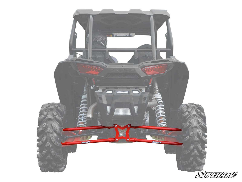 A rear view of an off-road vehicle showcases Polaris RZR RS1 Radius Arms with visible coil-over shocks and large rugged tires. The red suspension arms stand out beneath the chassis, and a SuperATV logo appears in the corner.