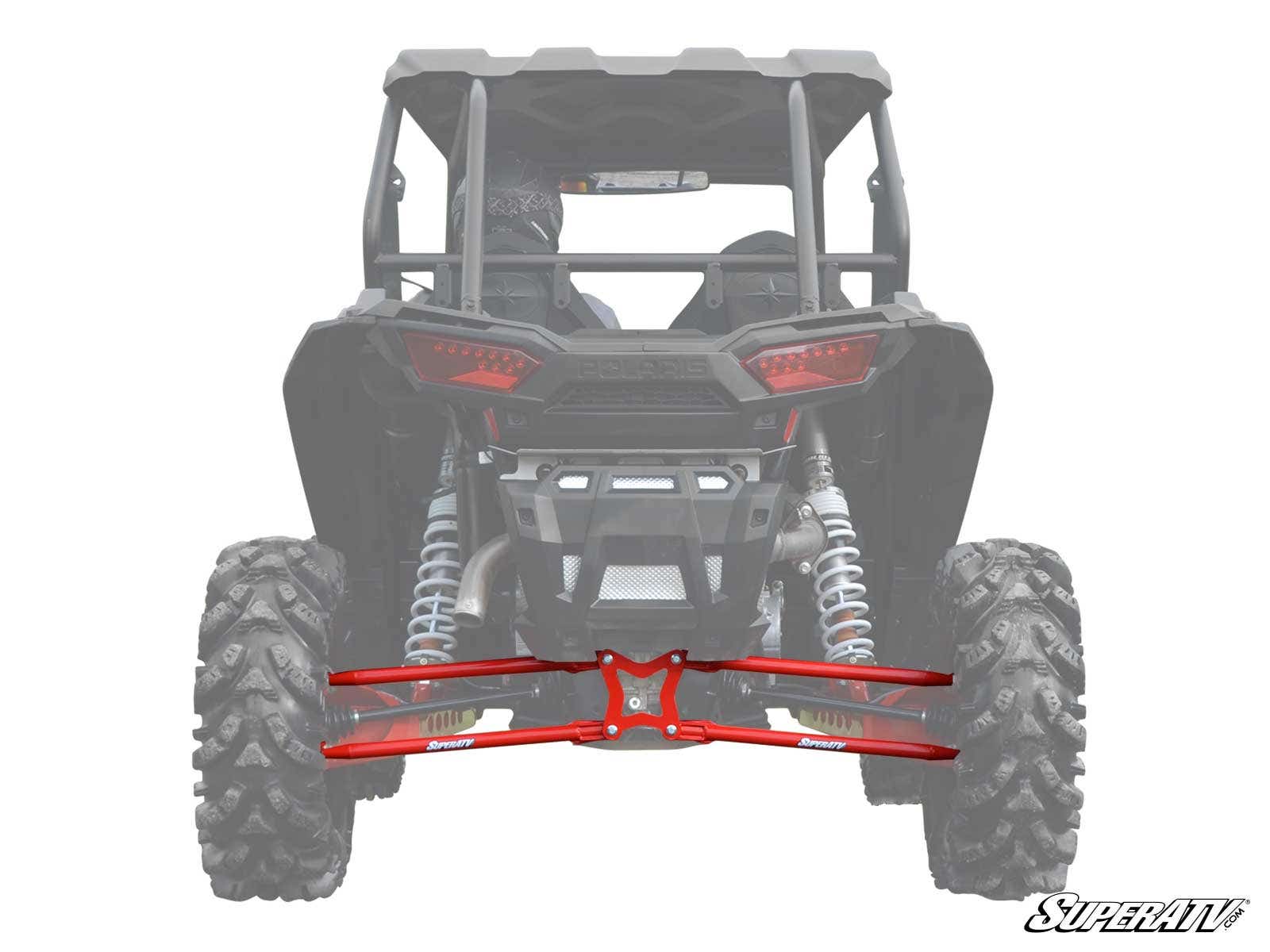 A rear view of a black off-road vehicle showcases red Polaris RZR XP Turbo Radius Arms and shocks. SuperATV branding appears in the bottom right corner, highlighting the upgraded suspension components.