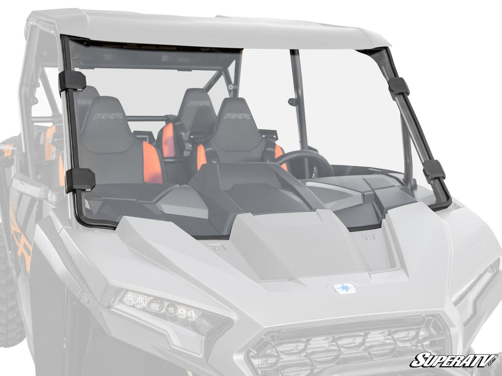 A Polaris RZR XP Full Windshield with black brackets is installed on a white UTV, showing two bucket seats with orange accents inside. The windshield fits securely and features the SuperATV logo at the bottom right corner.