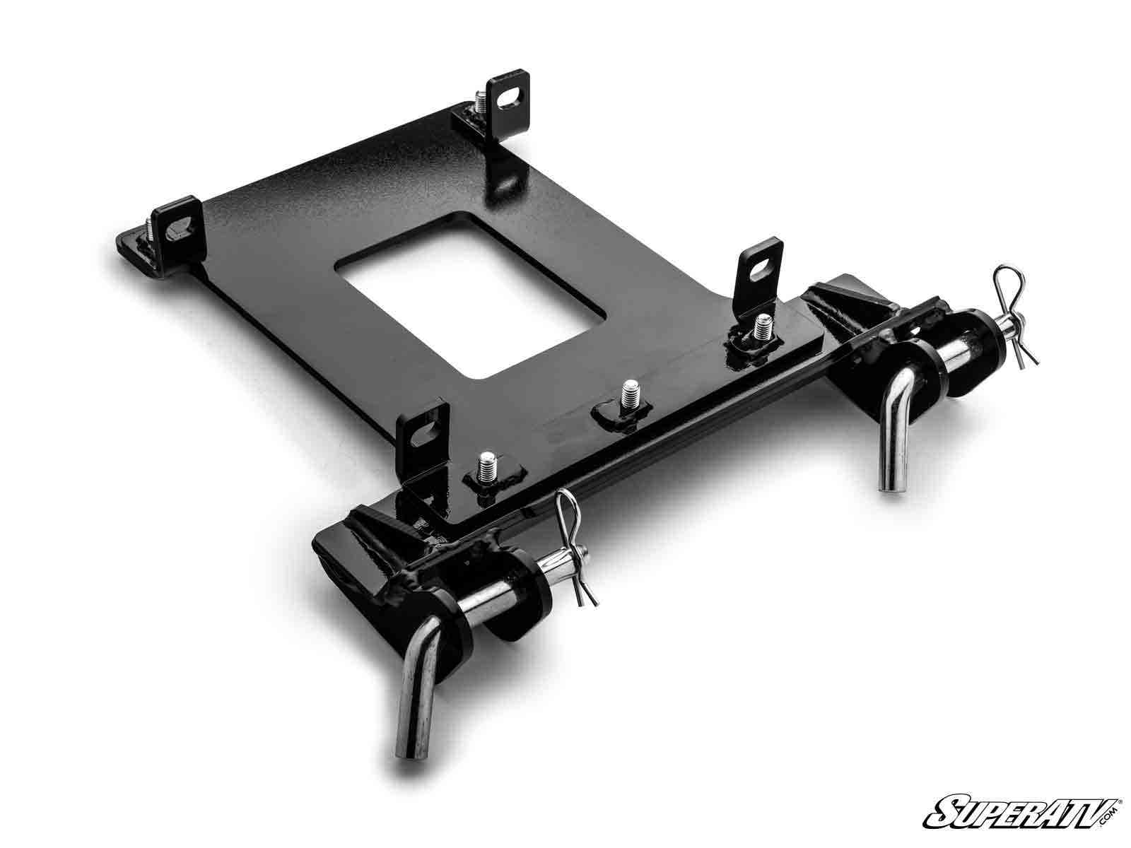 The Polaris RZR Trail S 1000 Plow Pro Snow Plow Mount is a black metal plate with bolts, brackets, and two cylindrical bars held by pins. It features a center rectangular cutout and the “SuperATV” logo at the bottom right on a white background.