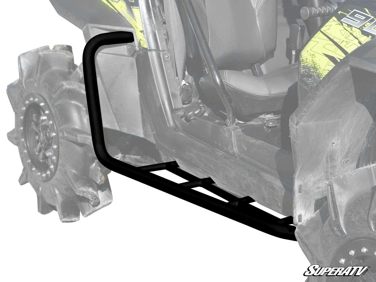 A close-up shows Polaris RZR XP 900 Heavy Duty Rock Sliding Nerf Bars in black metal attached to an off-road vehicle with large, rugged tires. The grayscale image highlights the nerf bars in full color, with the SuperATV logo in the corner.