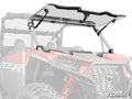 A Polaris RZR XP with a clear, flip-up windshield from SuperATV is shown in red. The background and parts of the vehicle are faded to highlight the Polaris RZR XP Flip Windshield and its mounting brackets, with the SuperATV logo in the lower right corner.