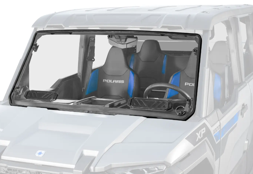 A close-up of a Polaris Xpedition Scratch Resistant Windshield on a gray off-road vehicle, showing two blue and black “Polaris” bucket seats, dashboard details, right-side steering wheel, and clear glass with wipers.