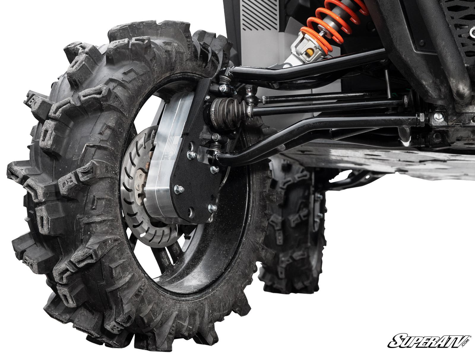 Close-up of the Polaris General XP 1000 8 Portal Gear Lift’s rear suspension and large, aggressive tire with deep treads. Features a bright orange coil spring, black control arms, and ventilated disc brake for enhanced durability and performance.