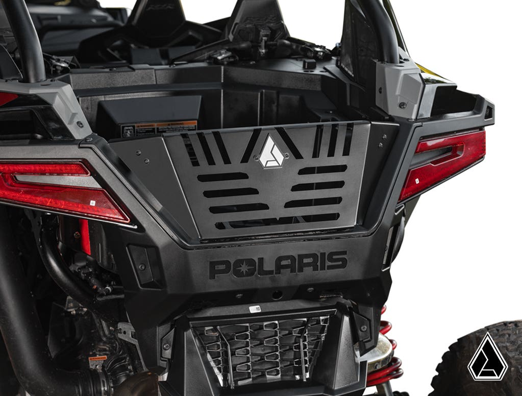 Close-up of the rear end of a black Polaris RZR Pro R fitted with the Assault Industries Bed Enclosure. The image shows red tail lights, rugged bodywork, cargo area, and logo on a vented tailgate against a plain white background.