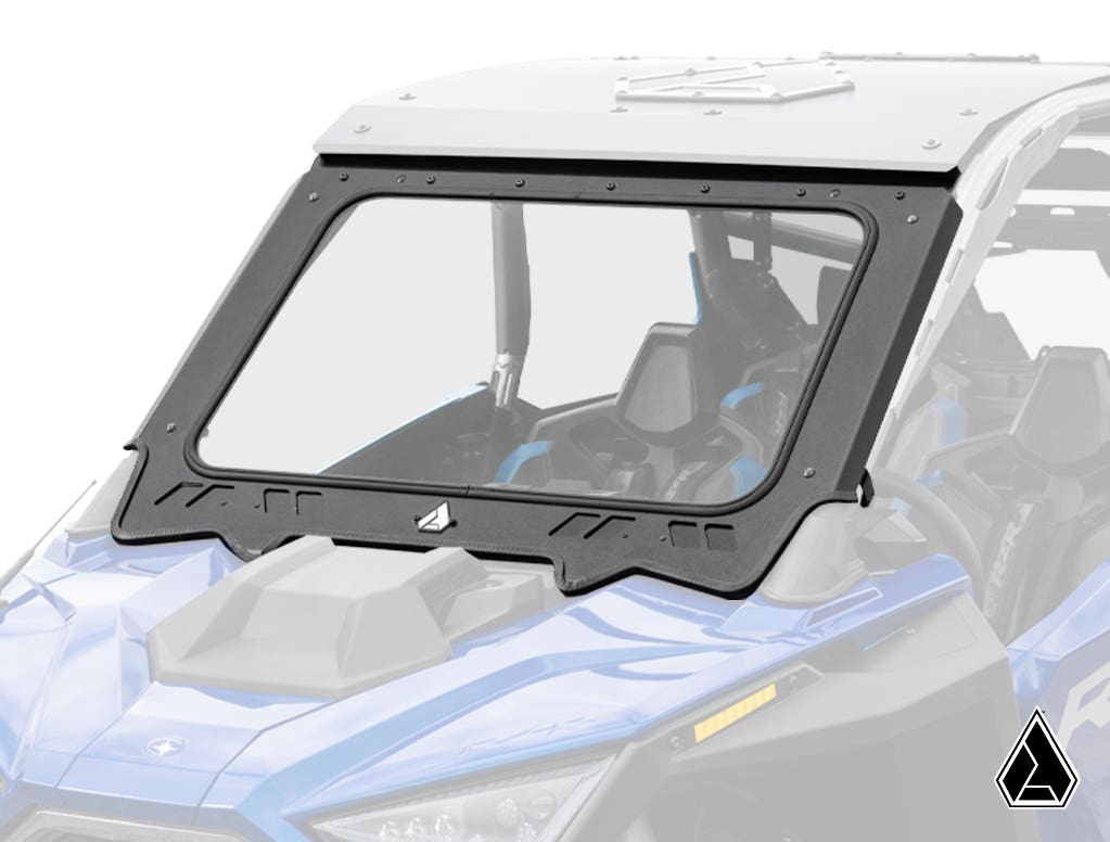 A close-up of the Assault Industries Polaris RZR Pro R 4 Glass Windshield, a clear, rectangular windshield with a black frame on a blue off-road vehicle. The shield covers the front seats and features a geometric logo in the bottom right corner.