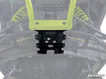 Close-up view of a Bobcat UV34 displaying suspension components, skid plate, A-arms, yellow shocks, and metal frame. The SuperATV logo appears in the lower right. The image highlights the central front area with the Frame Stiffener installed.