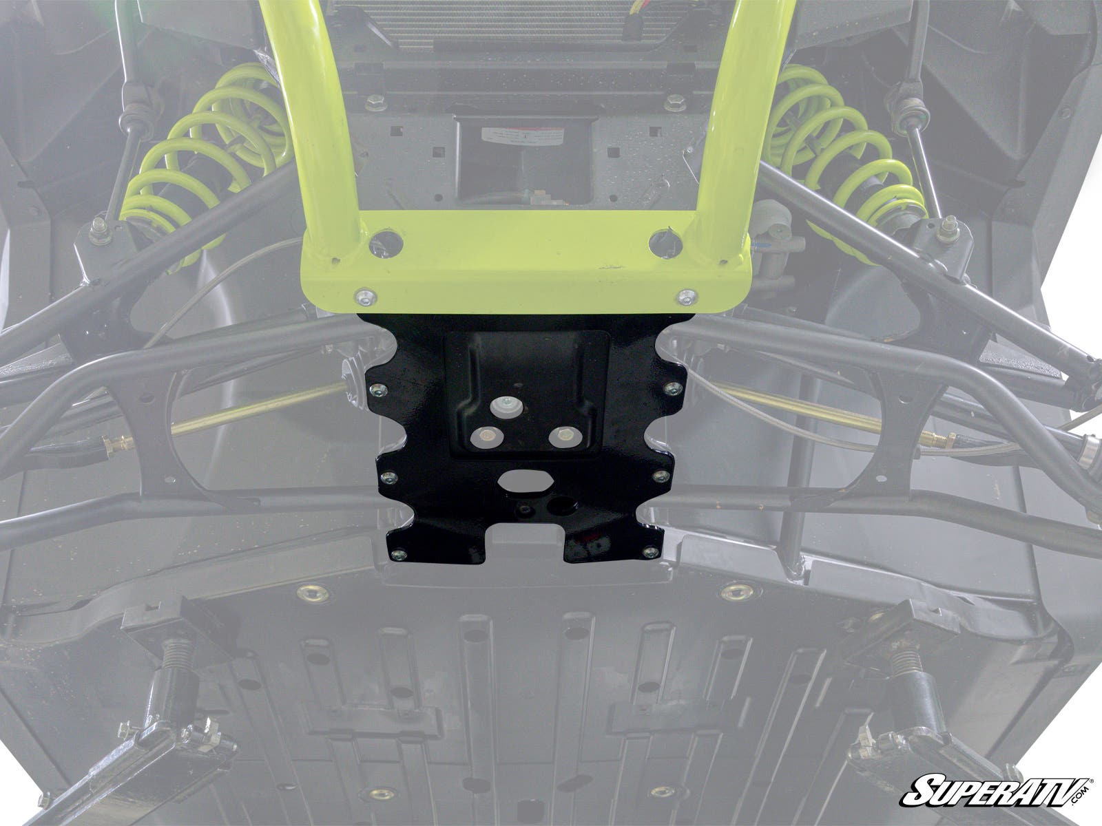Close-up view of a Bobcat UV34 displaying suspension components, skid plate, A-arms, yellow shocks, and metal frame. The SuperATV logo appears in the lower right. The image highlights the central front area with the Frame Stiffener installed.