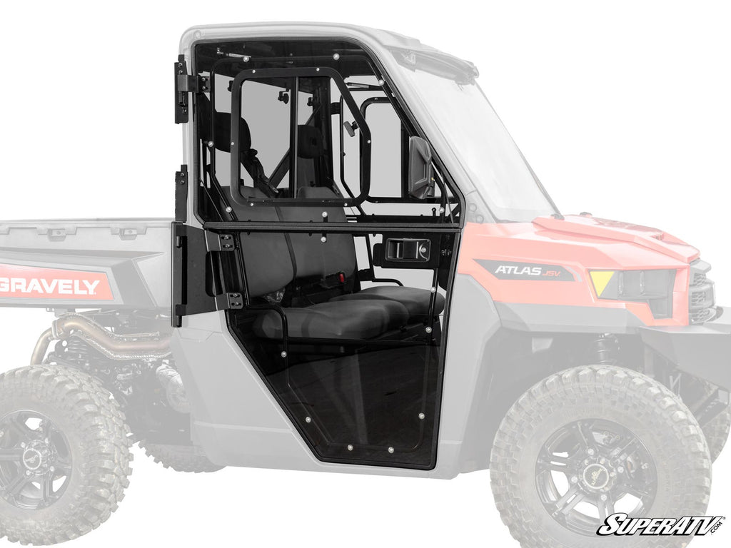 A side view of black framed, clear polycarbonate Gravely Atlas JSV 3400 Convertible Cab Enclosure Doors installed on a red and black utility vehicle shows hinges, latch, and paneling with the SuperATV logo in the bottom right corner.