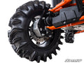 Close-up of a Polaris Ranger 1000 with a 4 Portal Gear Lift: rugged off-road tire with deep treads, visible suspension, shock absorber, and wheel hub. Orange frame and black side panel labeled Polaris, SuperATV logo at bottom right.