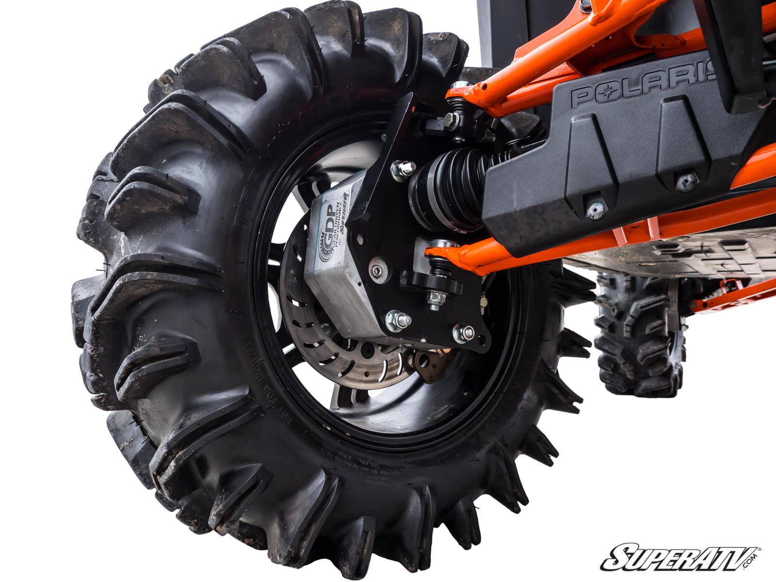 Close-up of a Polaris Ranger 1000 with a 4 Portal Gear Lift: rugged off-road tire with deep treads, visible suspension, shock absorber, and wheel hub. Orange frame and black side panel labeled Polaris, SuperATV logo at bottom right.
