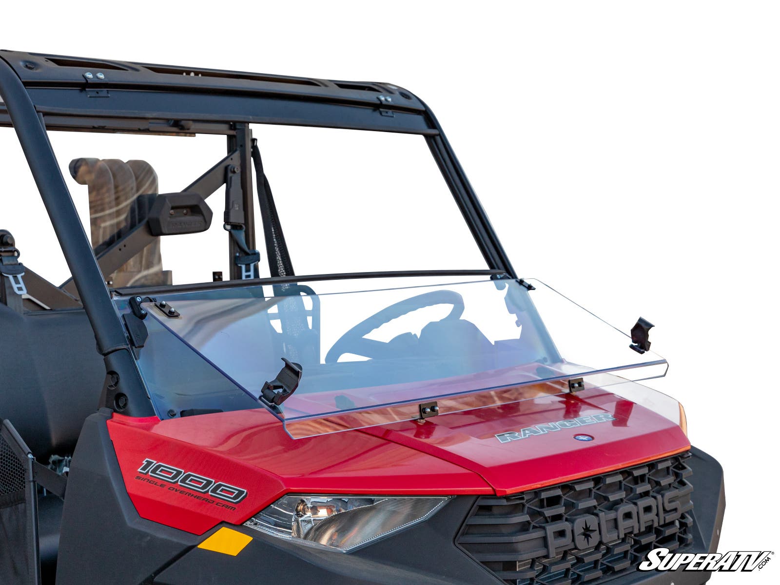 A red Polaris Ranger 1000 features a Polaris Ranger XP Kinetic 3-in-1 Windshield, clear and half-sized, mounted at the front with black brackets. The windshield covers the dashboard and steering wheel, displaying a SuperATV logo at the lower right.