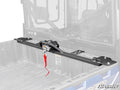 A close-up of the Polaris Ranger 570 Bed Winch with a red strap is mounted in the cargo bed of a blue utility vehicle. The vehicles bed and cab interior are visible, with the SuperATV logo at bottom right and a faded background for emphasis.