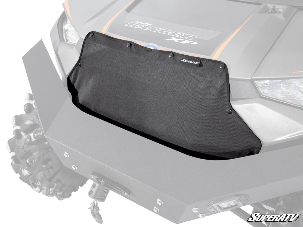 A Polaris Ranger XP 1000 Grille Cover in black mesh is mounted on the front of a gray off-road vehicle with rugged tires, an angular hood, and the SuperATV logo visible in the bottom right corner.