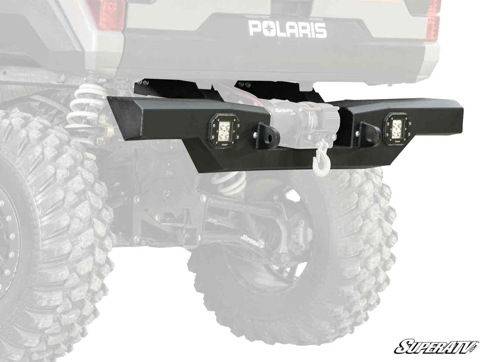 A Polaris Ranger XP Kinetic Winch-Ready Rear Bumper with LED lights and a winch hook is mounted on an off-road vehicle. The setup features large rugged tires and exposed suspension springs, with the SuperATV logo displayed in the lower right corner.