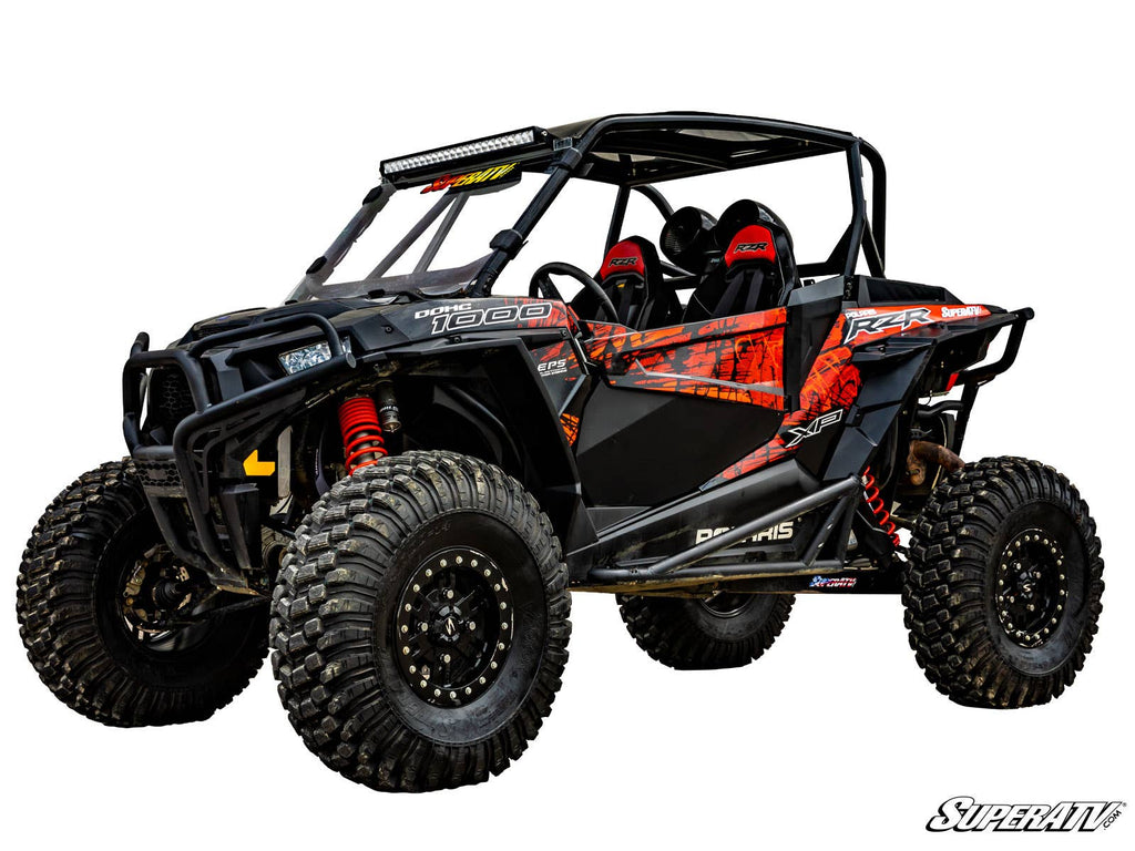 A Polaris RZR XP 1000 with a 3 Lift Kit, featuring black and orange accents, rugged tires, red coil shocks, safety bars, roof LED light bar, and graphic decals. Photographed on white with the SuperATV logo in the corner.