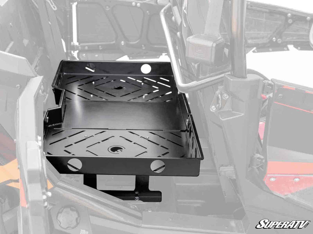 A Polaris RZR XP 4 Turbo S Rear Seat Cargo Rack with black metal slotted surfaces and round holes is mounted next to the drivers seat inside the cab; part of the vehicle interior is visible in the background.