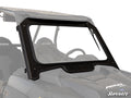 A Polaris RZR XP 1000 Glass Windshield with tinted glass, black metal frame, and wiper is mounted on a dark RZR side-by-side. The SuperATV logo is in the bottom right corner on white, with part of the vehicle’s interior visible.