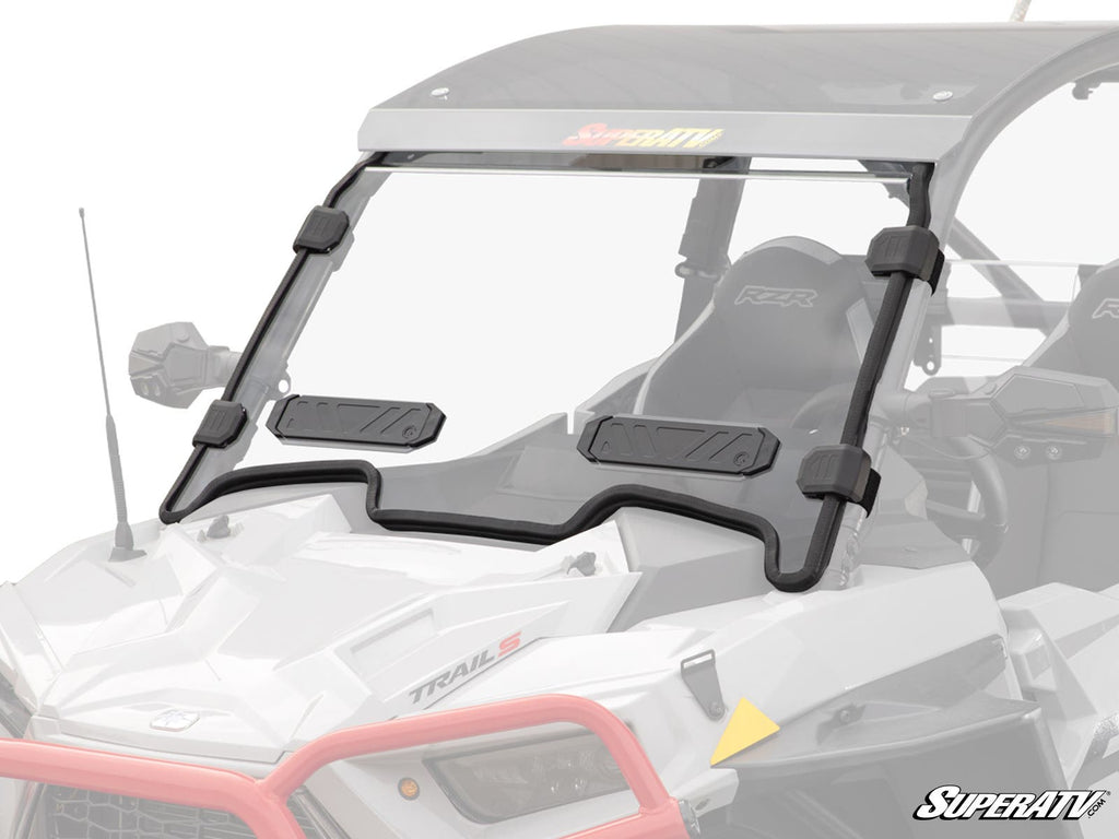 A Polaris RZR Trail S 900 Vented Full Windshield with a black frame, two black vent panels, and four clamps is mounted on a white utility vehicle with bucket seats, roll cage, and SuperATV branding in the lower right corner.