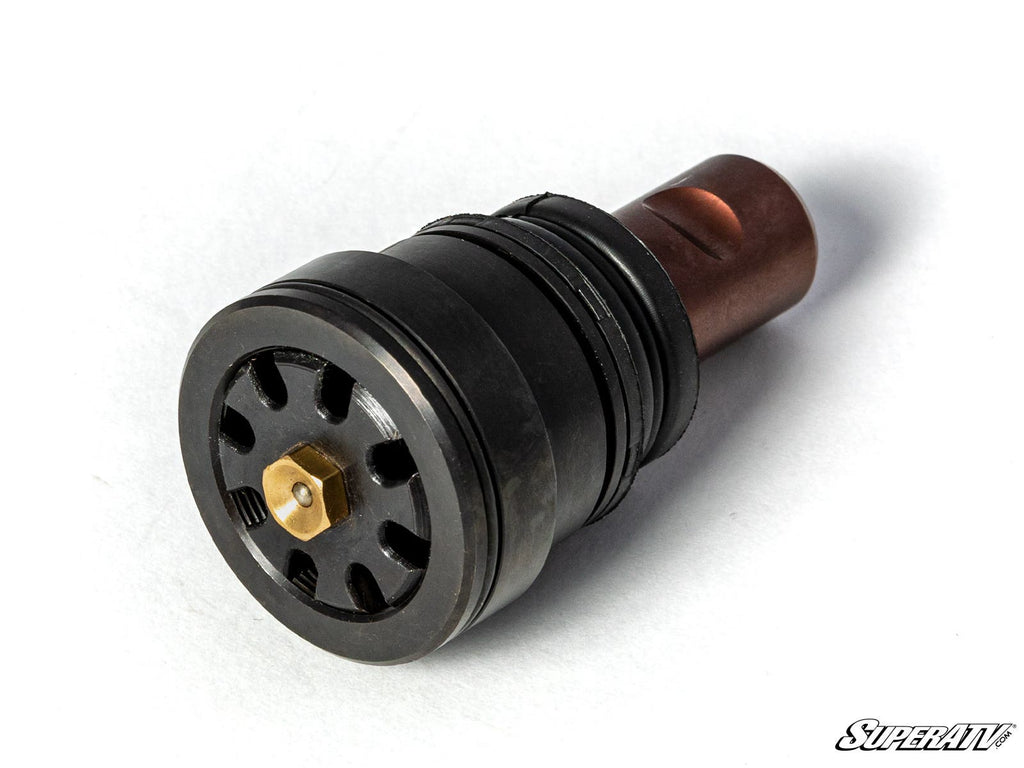 A close-up of a black, cylindrical Polaris RZR Pro R Ball Joint with a hexagonal brass center, circular vents, and a copper end on a white surface. The SuperATV logo appears in the lower right corner.