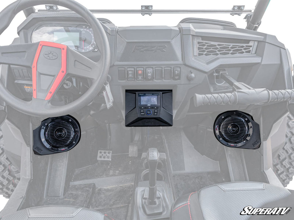 Interior view of a Polaris RZR with the MTX Polaris RZR THUNDER Sound System, showing the dashboard, steering wheel, center console, two black speakers by the footwells, control switches, and the SuperATV logo in the bottom right corner.