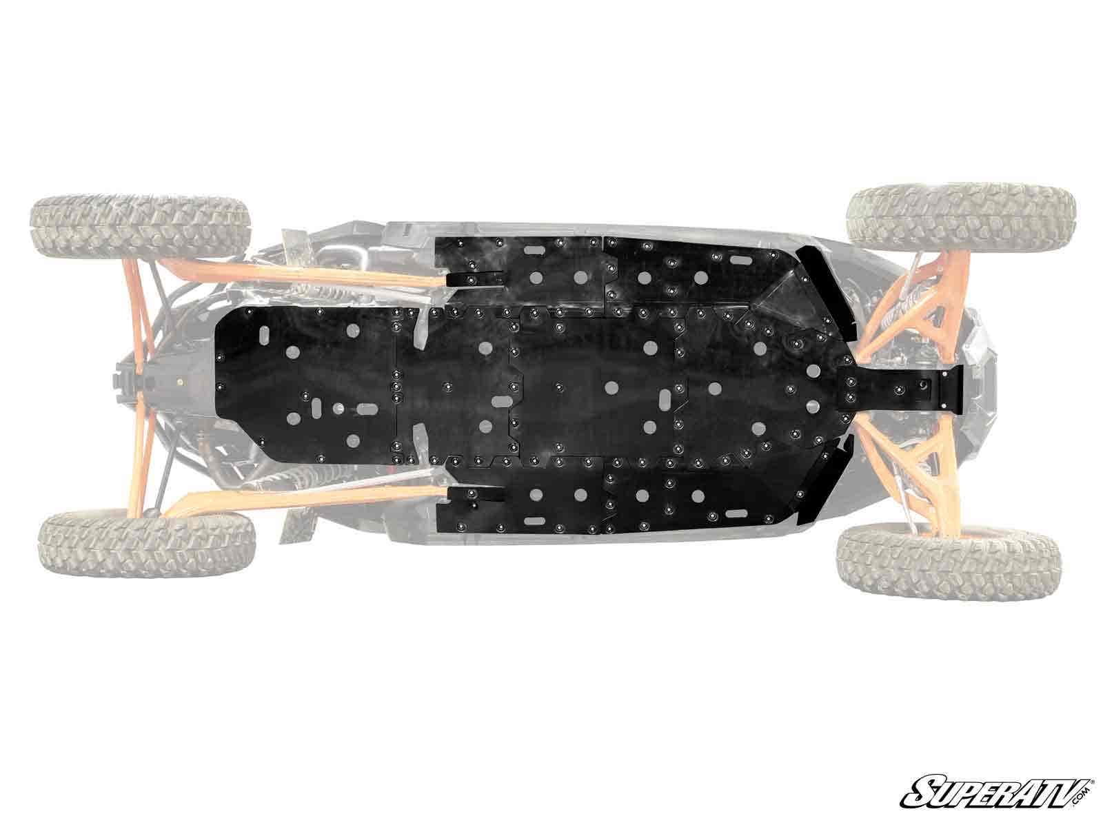 Top-down view of a Polaris RZR Pro R 4 Full Skid Plate installed on an off-road vehicle chassis with large, rugged tires. The black metal skid plate covers the underside, protecting the frame and suspension. SuperATV logo is in the bottom right.