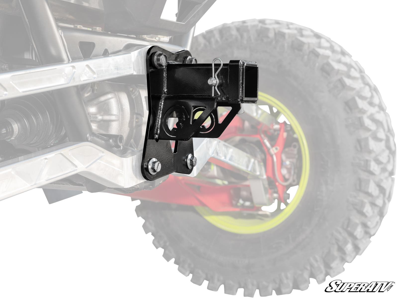 Close-up of a Polaris RZR Pro R Rear Receiver Hitch, mounted on the rear suspension frame of an off-road vehicle with large tires. Secured with bolts and a hitch pin, parts of the vehicle are faded to highlight the hitch.