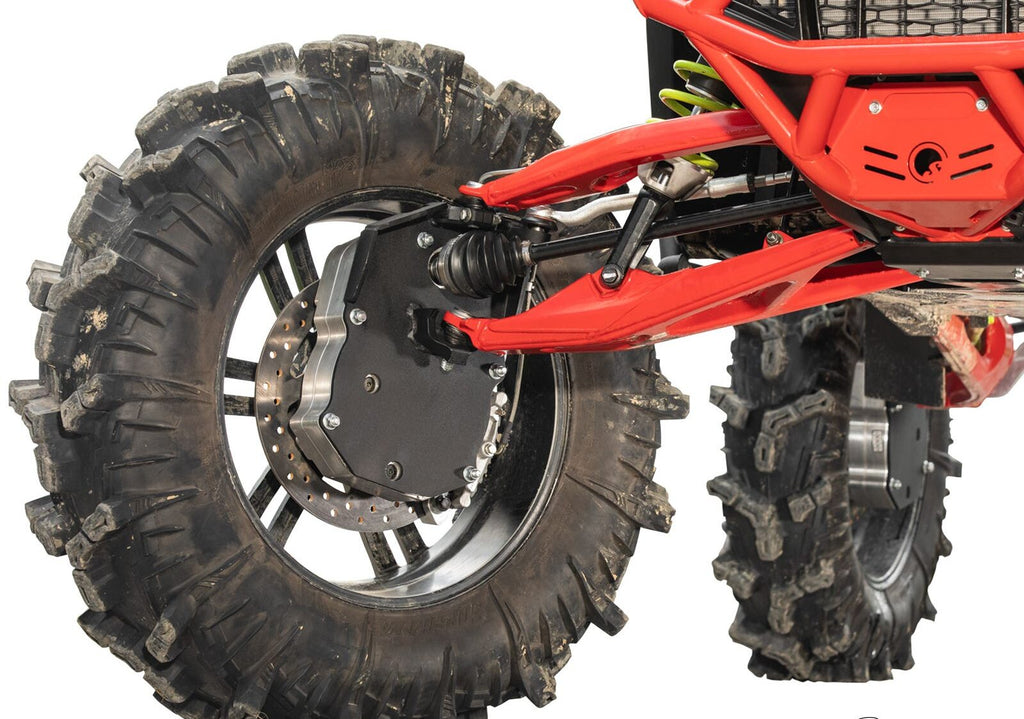 Close-up of a Polaris RZR Turbo R 8 Portal Gear Lift showing rugged suspension arms, black wheel hub with bolts, brake disc, and large, deeply treaded tires covered in dirt from recent off-road use.