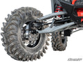 Close-up of a Polaris RZR Pro R 6 Portal Gear Lift suspension system featuring a rugged, deep-tread tire, exposed shock absorber with red spring, metallic control arms, and brake components. SuperATV logo appears in the bottom right corner.