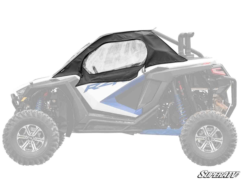 A Polaris RZR Turbo R Primal Soft Cab Enclosure Upper Door in black, with a clear window, is installed on the side of a white and blue ATV. Only the enclosure is fully colored; the rest of the vehicle is faded. The SuperATV logo is at the bottom right.