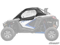 A Polaris RZR Turbo R Primal Soft Cab Enclosure Upper Door in black, with a clear window, is installed on the side of a white and blue ATV. Only the enclosure is fully colored; the rest of the vehicle is faded. The SuperATV logo is at the bottom right.
