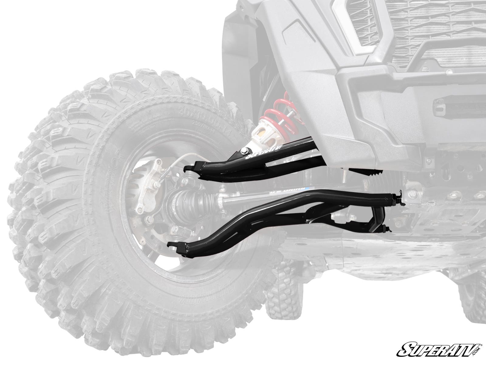 A close-up of Polaris RZR XP 1000 High Clearance 2 Forward Offset A-Arms installed on the front left wheel of an off-road vehicle with a large, deep-tread tire. The shiny A-Arms and SuperATV logo stand out against the faded background.