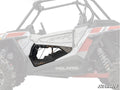 A close-up highlights Polaris RZR 900 S Clear Lower Doors installed on the drivers side, revealing the vehicles interior through a geometric cutout. The rest of the off-road vehicle is faded, with a SuperATV logo in the bottom right.