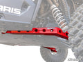 A close-up of Polaris RZR RS1 High Clearance Rear Trailing Arms installed beneath a Polaris off-road vehicle, bolted near the suspension and large tire with visible chassis and mechanical components.