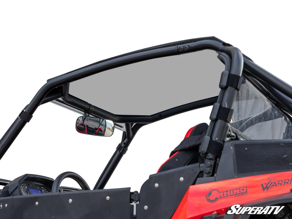 A close-up of the black metal roll cage and Polaris RZR XP Turbo S Tinted Roof on a red off-road vehicle, showing a clear rearview mirror, padded bars, seatbacks, and partial SuperATV and Rhino logos.