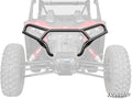 A Polaris RZR XP Front Bumper, black and tubular, is shown in full color on a greyed-out side-by-side UTV with large knobby tires, visible suspension coils, and the SuperATV logo in the bottom right corner.