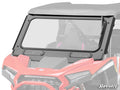 A Polaris RZR XP Glass Windshield with a black frame is mounted on the front of a red off-road vehicle, covering the driver and passenger seats. The SuperATV logo is in the lower right corner, set against a white background.