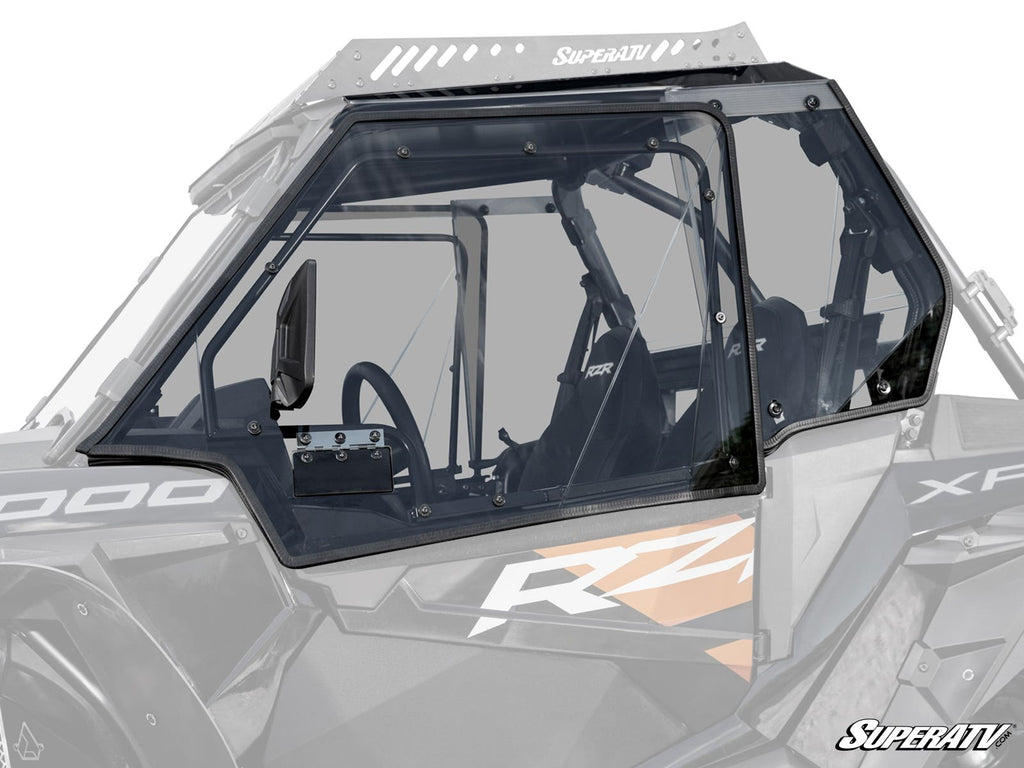 A close-up of Polaris RZR XP 1000 Hard Cab Enclosure Upper Doors shows tinted polycarbonate panels, a black frame, and interior details including seats, a partially visible steering wheel, and dashboard on a RZR side-by-side vehicle.