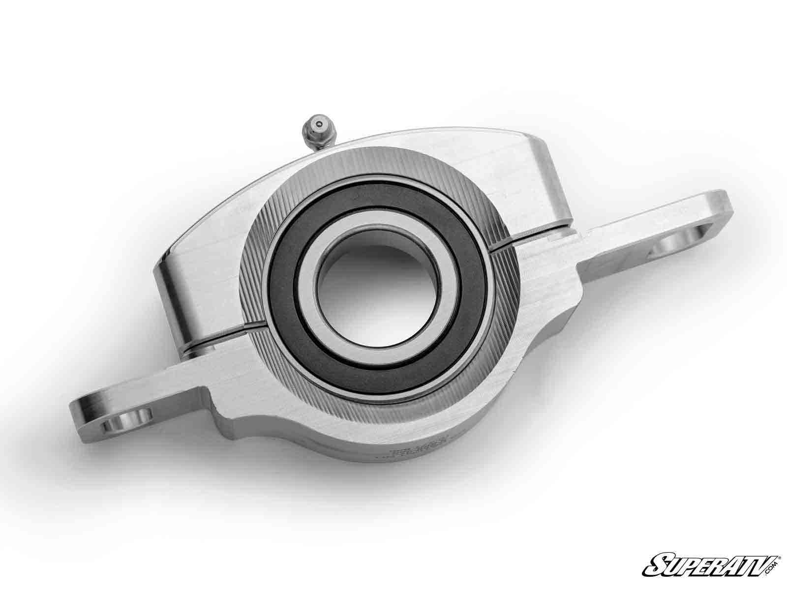 A close-up of the Polaris RZR PRO XP Heavy-Duty Carrier Bearing shows its silver metal body, circular center bearing, and two mounting arms. The SuperATV logo appears in the bottom right on a plain white background.