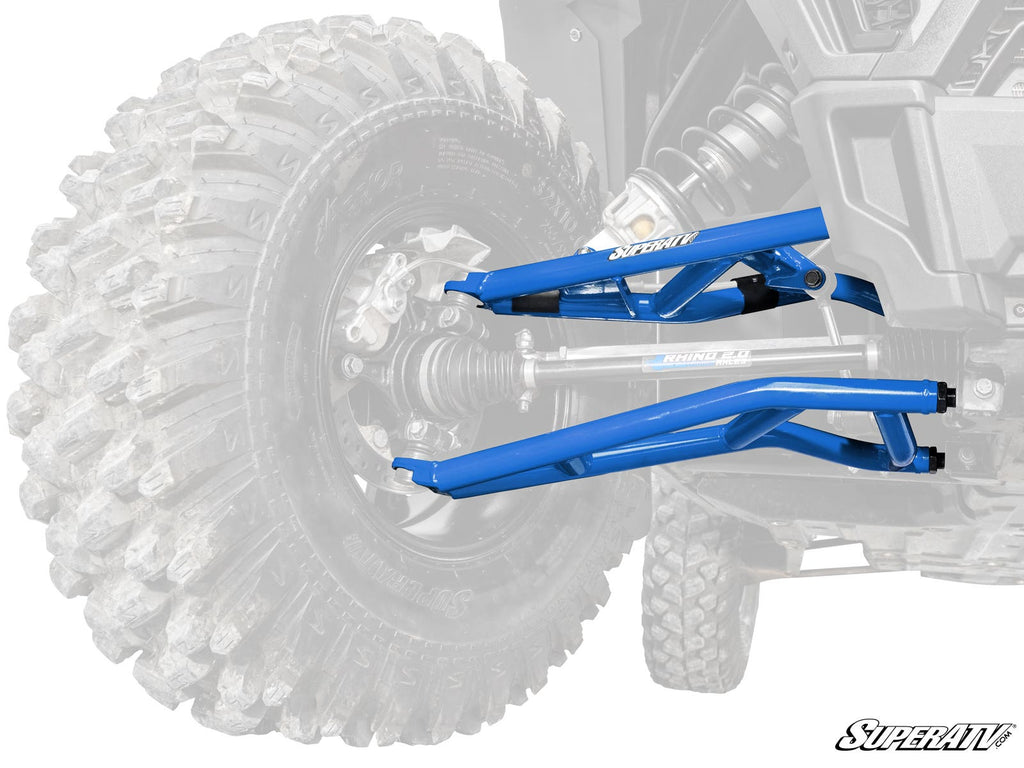 A close-up of Polaris RZR XP Turbo High Clearance 1.5 Forward Offset A-Arms in metallic blue, installed on the front wheel of an off-road ATV. The SuperATV logo is visible on the A-arm, highlighted with the tire and vehicle background faded out.