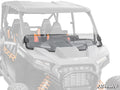A Polaris RZR XP Half Windshield is mounted on a black side-by-side with orange suspension springs, spanning the front over the dashboard and steering wheel. The SuperATV logo appears in the lower right corner.
