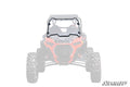 A Polaris RZR XP Turbo S Scratch-Resistant Full Windshield is installed on a red Polaris RZR side-by-side, with the windshield and mounting hardware shown in full color, the vehicle faded, and the SuperATV logo in the bottom right.