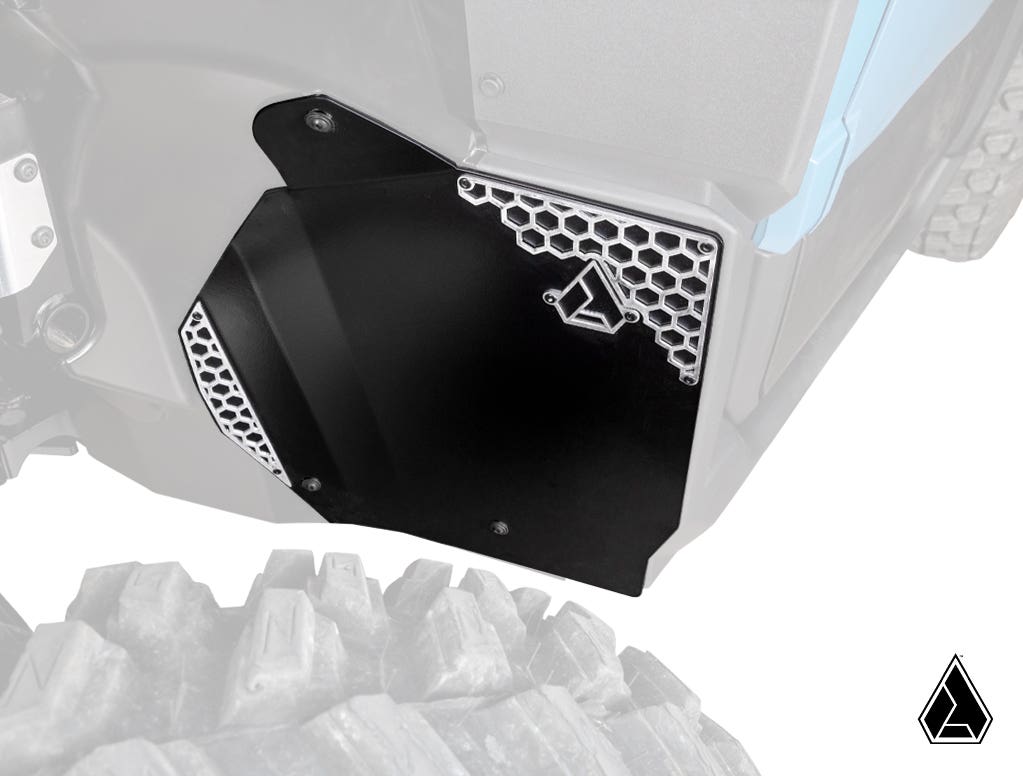 A close-up of Assault Industries Polaris Xpedition Inner Fender Guards highlights a black panel with a honeycomb-patterned metal accent and geometric logo. The vivid panel and nearby textured tire stand out against a desaturated background.