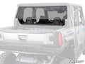 A Polaris Xpedition XP Rear Windshield, tinted and clear with black edges, is installed on an off-road utility vehicle, covering the rear cabin window. Two black seats are visible inside, with the SuperATV logo in the bottom right corner.