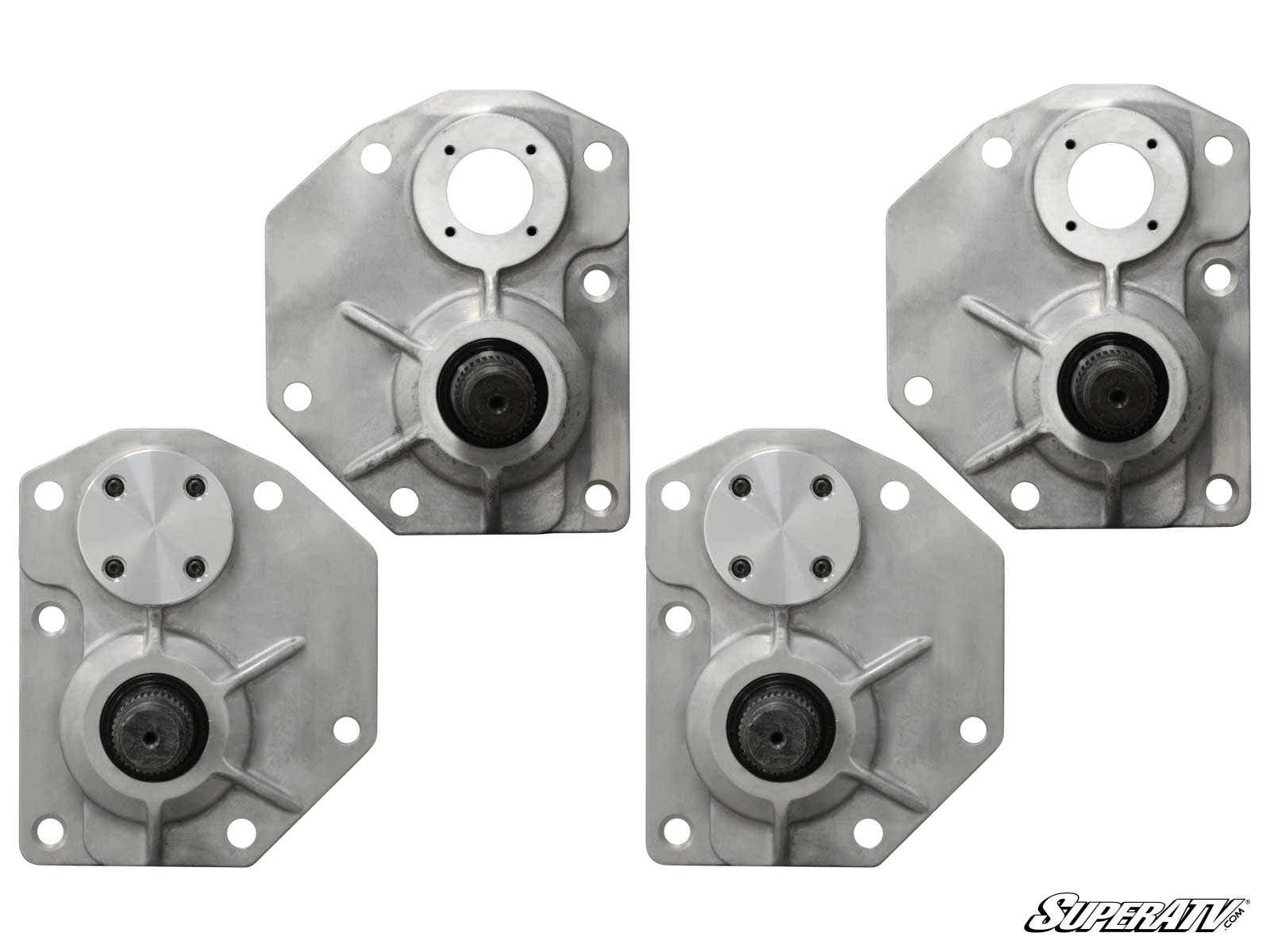 Four silver, angular metal brackets with circular hubs and bolt holes are arranged in a grid on a white background. Each bracket has a black central bearing and ridges. The SuperATV logo appears beside the Arctic Cat Portal Gear Lift Conversion Kit - Gen 